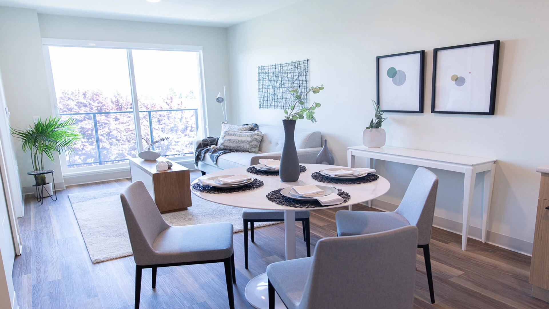 A dining room table and living room view of a Wisteria Place senior apartment