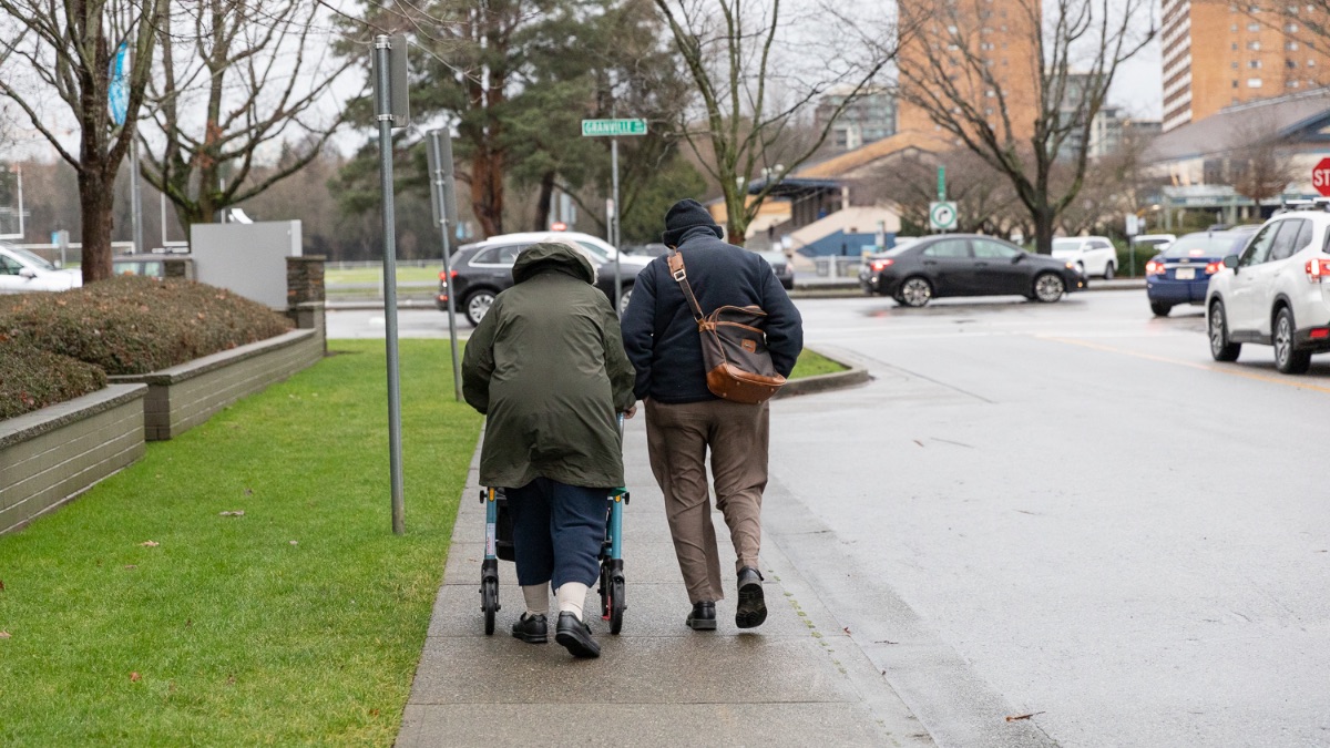 An couple walking on a sidewalk outside a retirement home