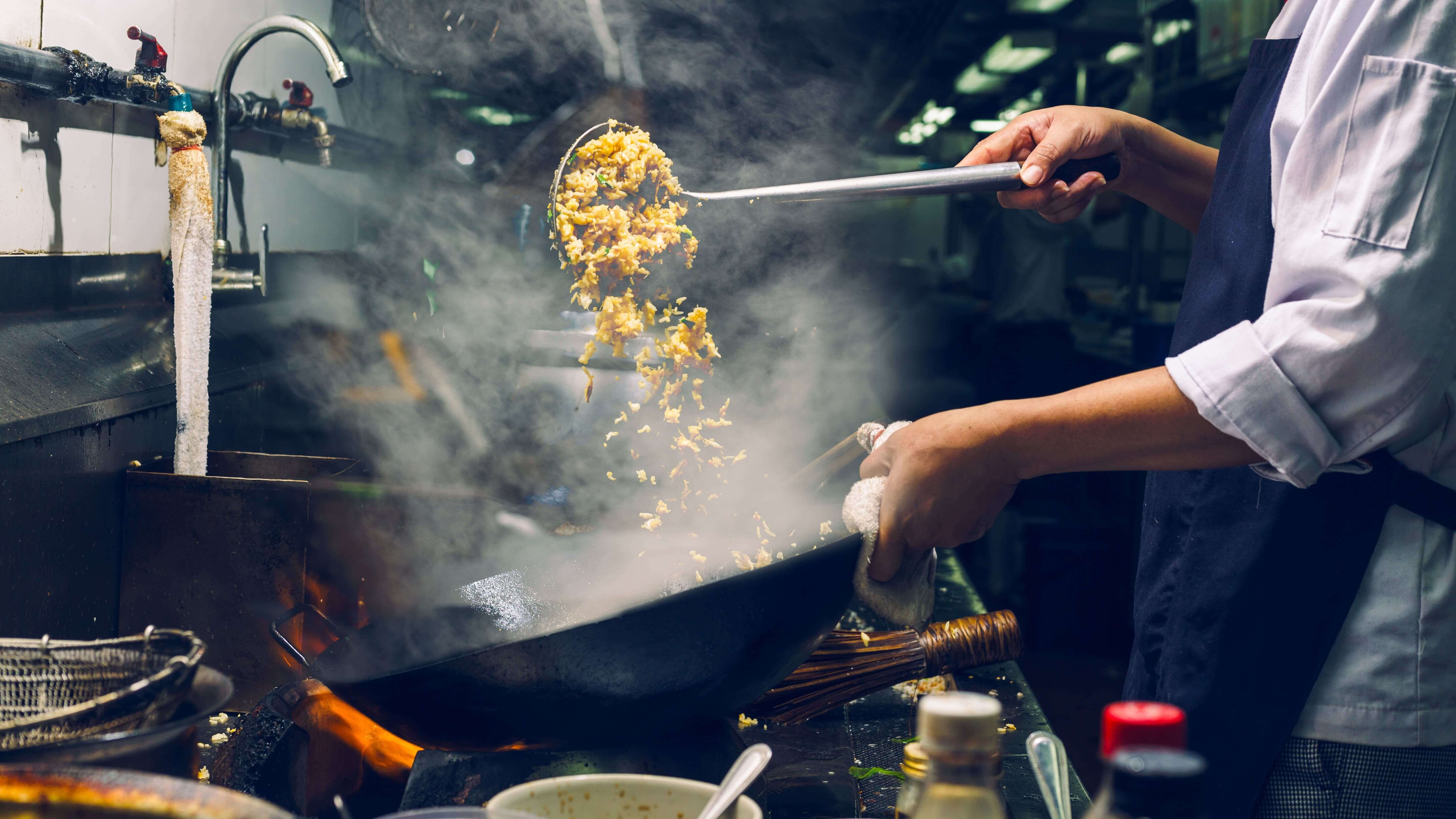 A cook making fried rice in a wok