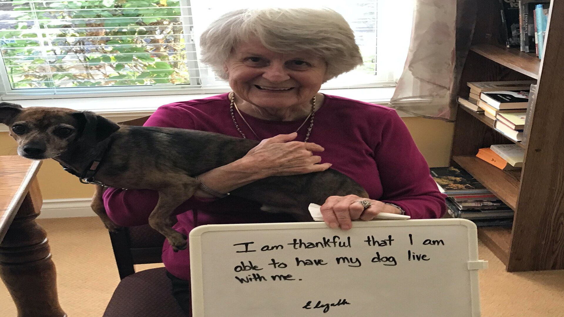 An elderly woman with her dog on thanksgiving day in senior living