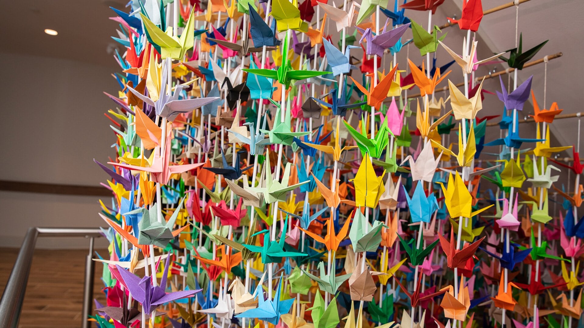 Hanging artwork made of origami birds in a rainbow of colours