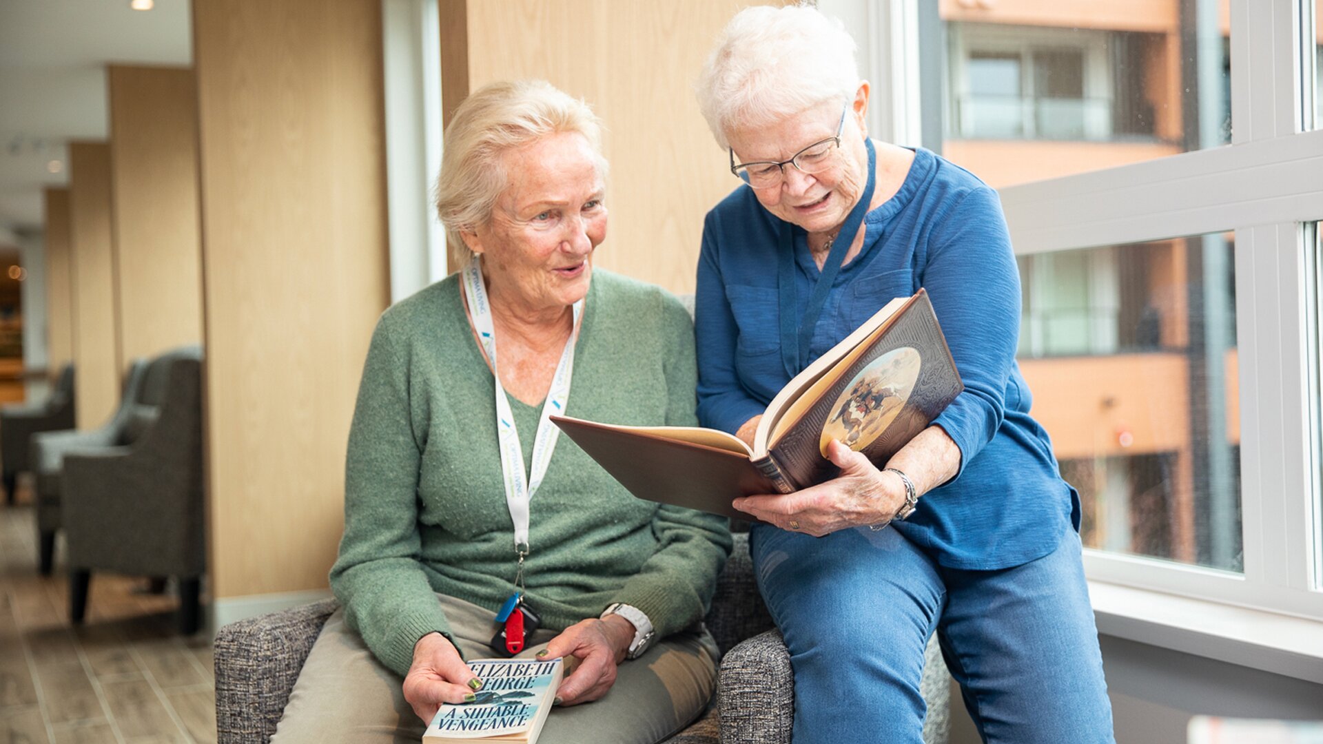 Two elderly women looking through a book together