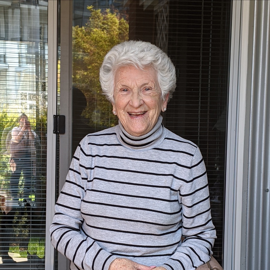 An old woman with a smile and a black-striped sweater in senior living