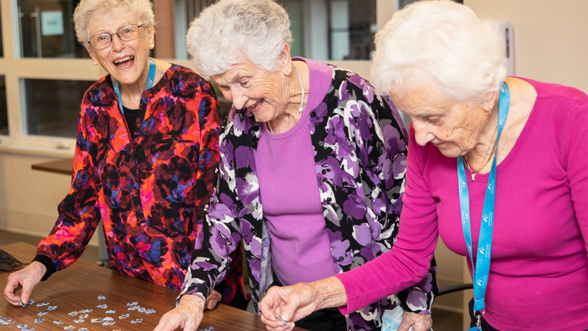Three women do a puzzle, a fun hobby for elderly