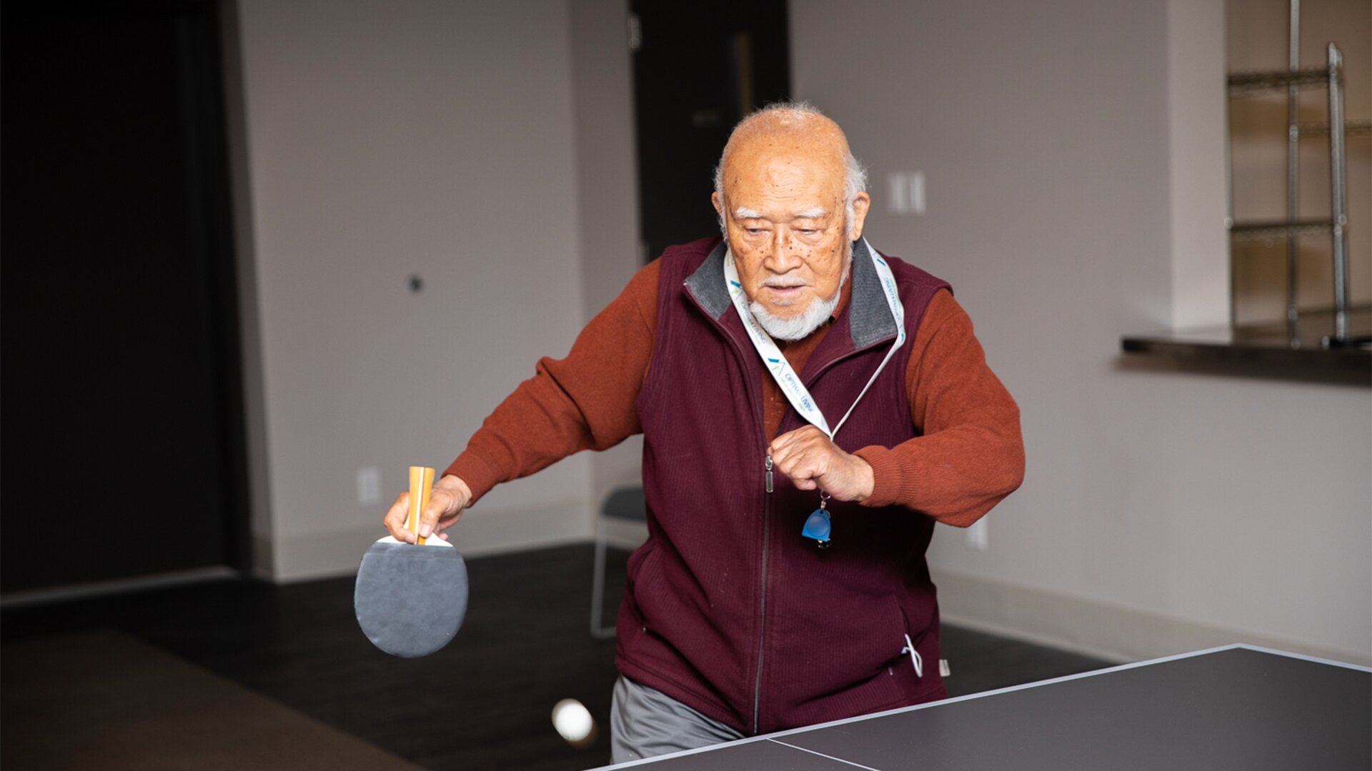 An elderly man playing ping pong