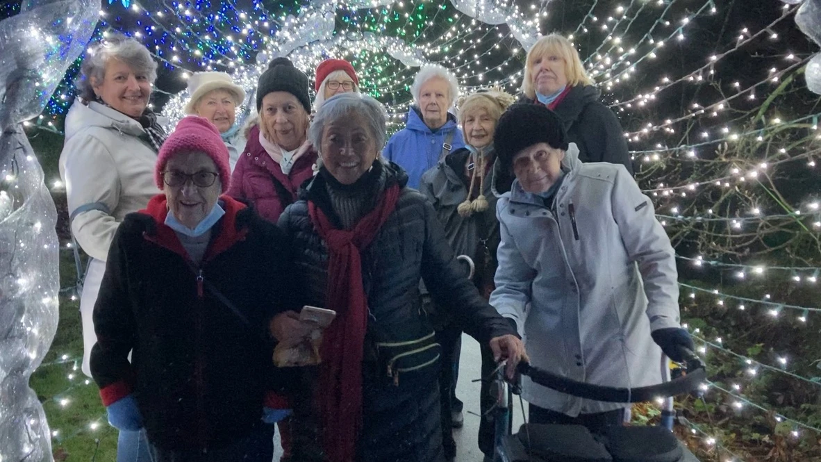 A group of elderly women celebrating Christmas with lights outside senior living