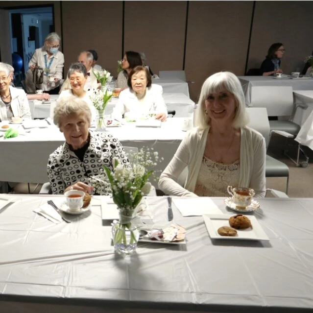 Elderly people wearing white dresses and having breakfast at Wisteria place senior home