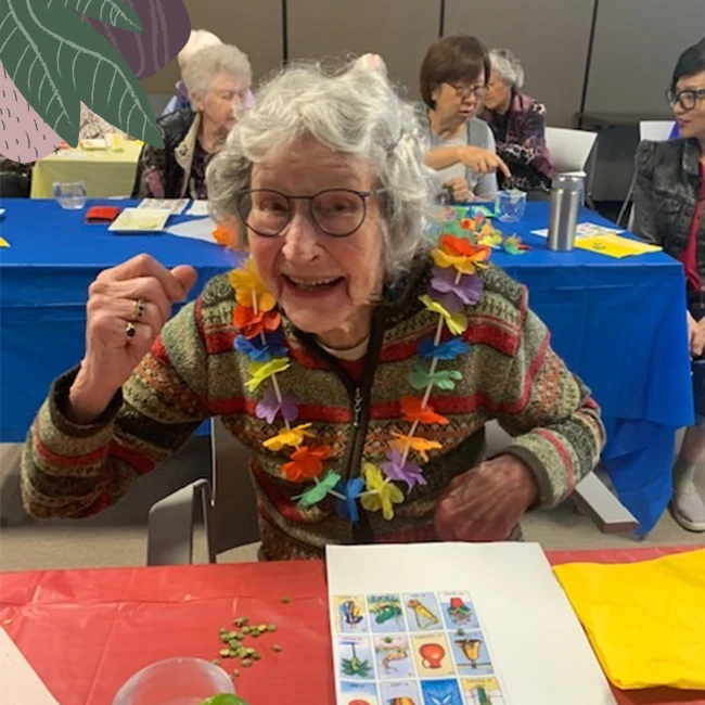 An elderly lady wearing colourful flowers in senior living