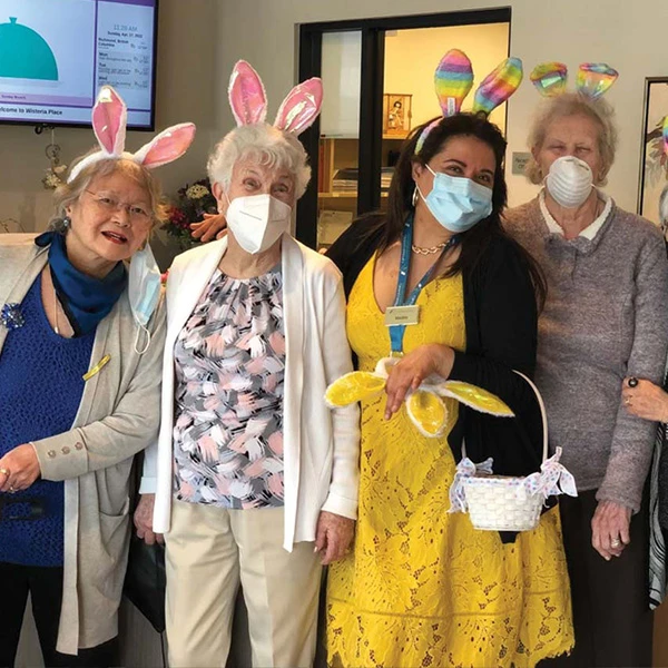 Seniors posing in Easter Bunny ears along with the GM of Wisteria Place