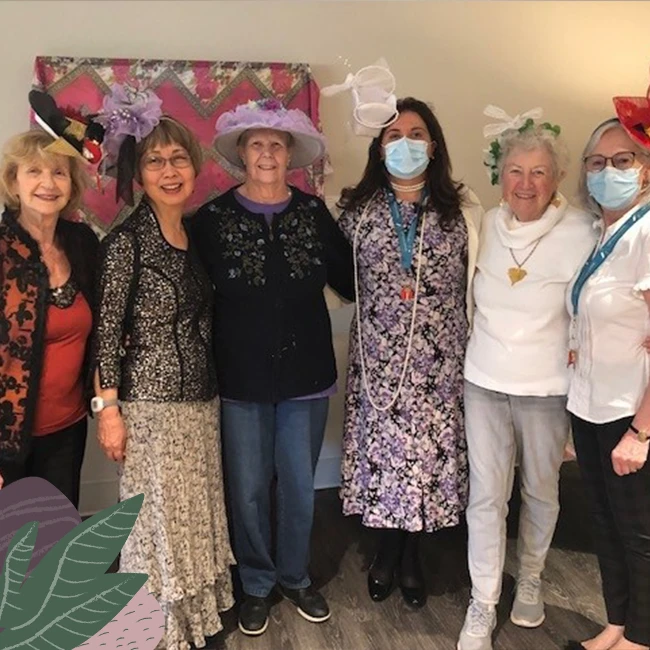 A group of elderly women wearing hats in senior living