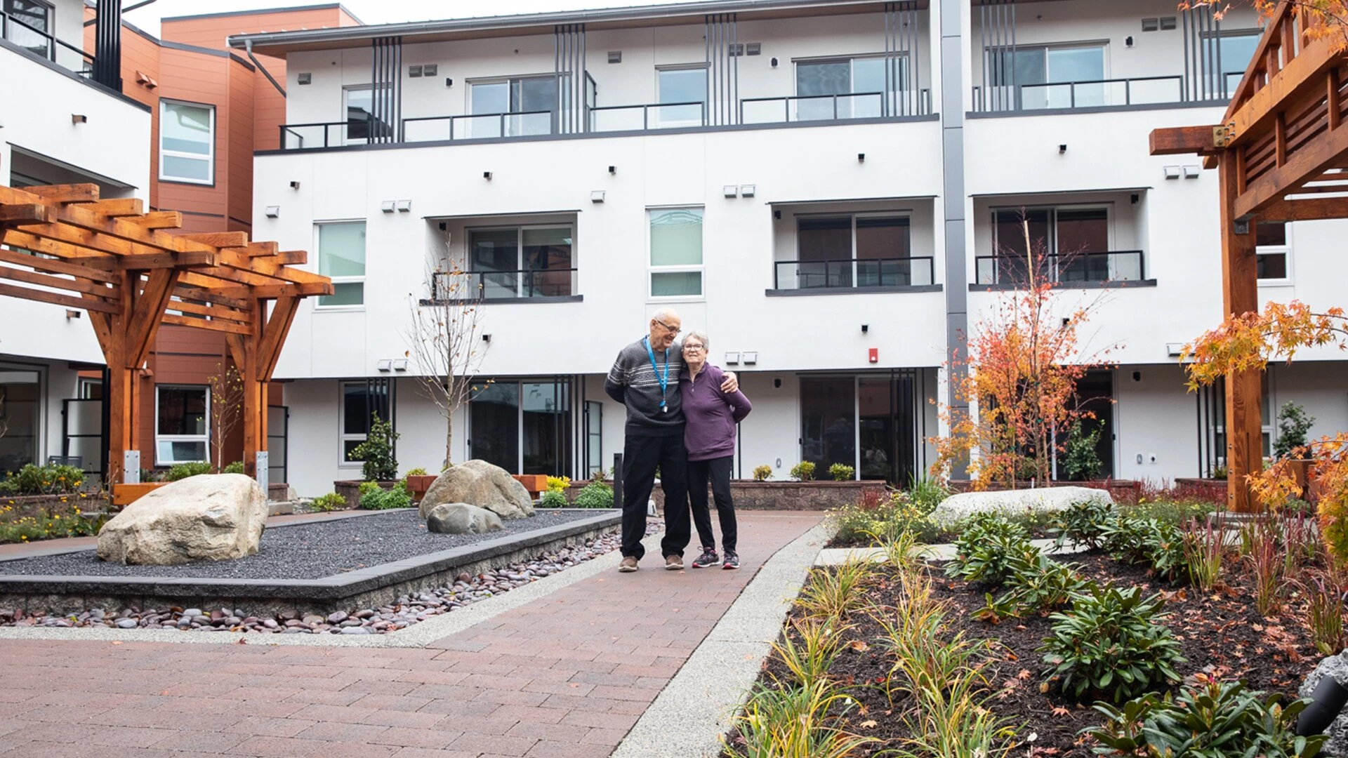 An elderly couple standing in Wisteria Place retirement home courtyard