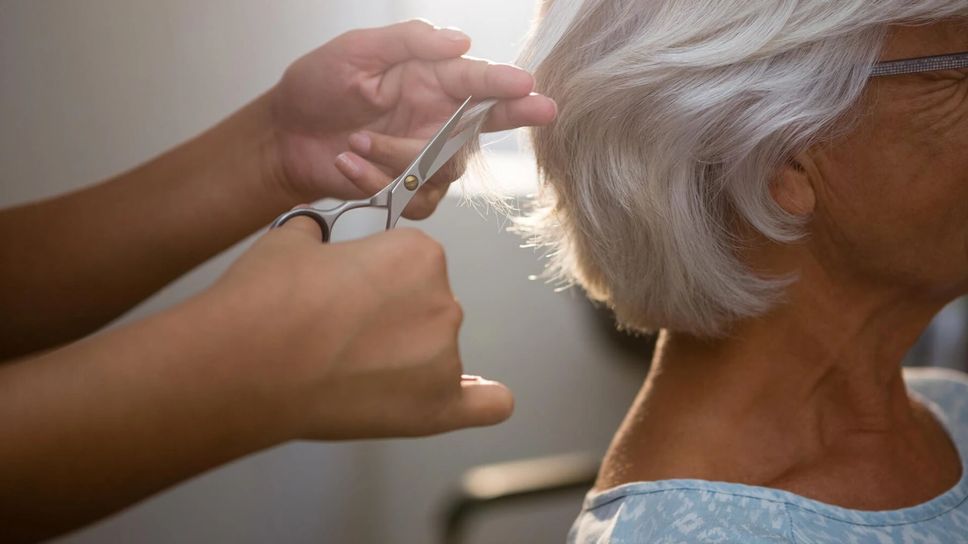 A hairdresser giving an elderly woman a haircut