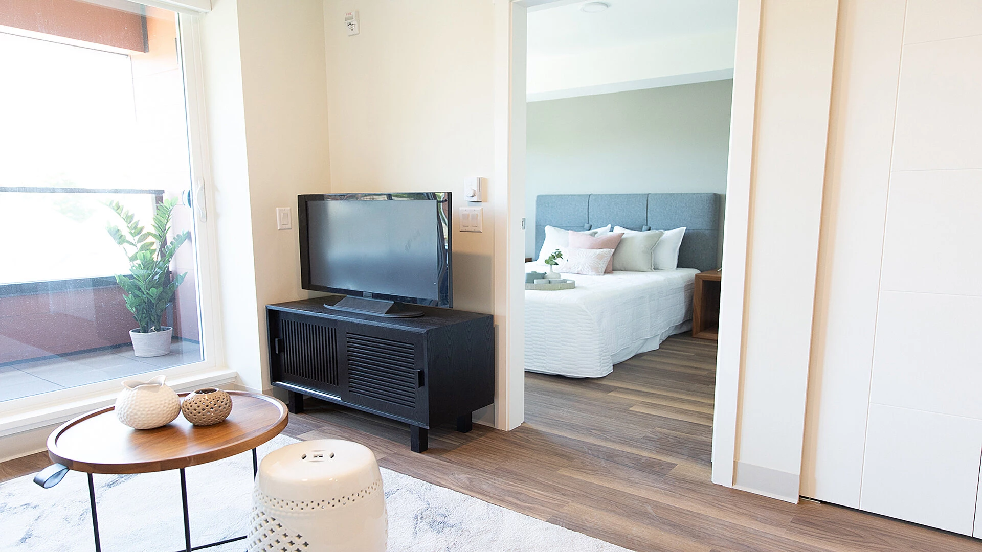 A living room tv and entrance to a Wisteria Place suite bedroom