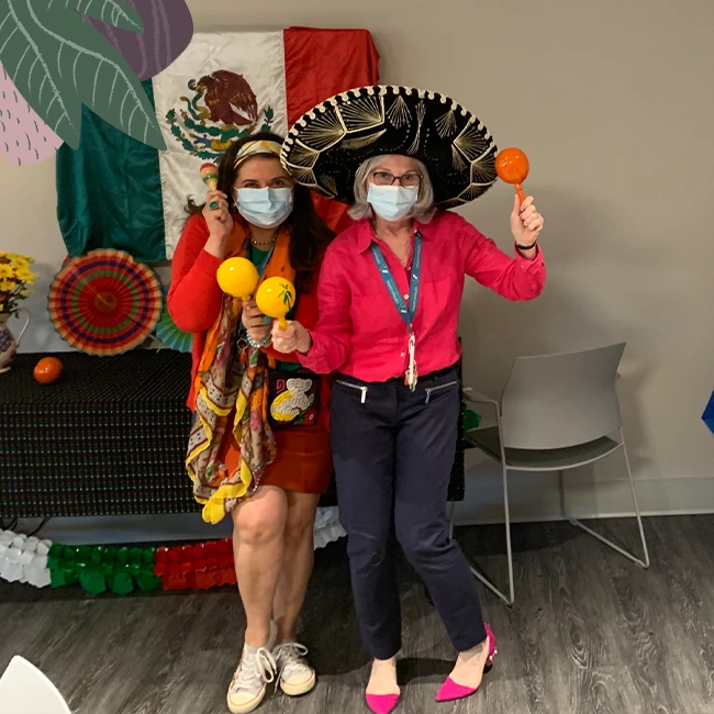 Two ladies wearing costumes in a senior home