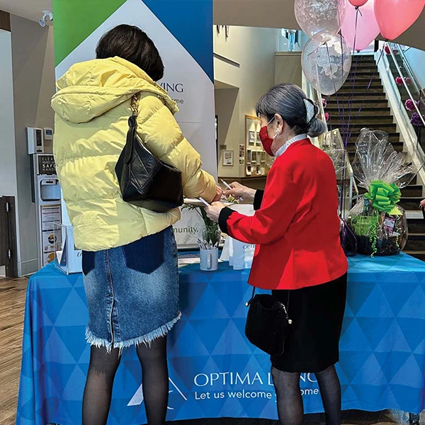 Two seniors visiting the Optima Living table at the Wisteria Place open house