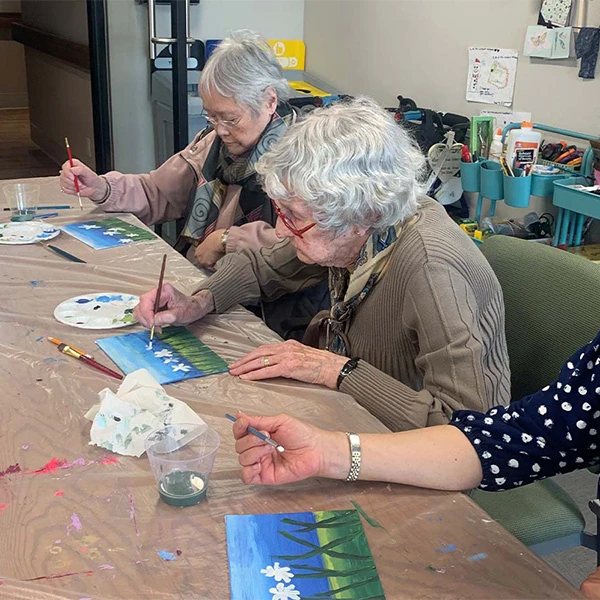 Seniors painting some flowers together.