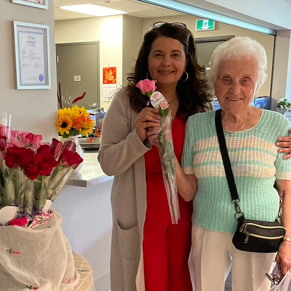 Senior woman standing with GM along with some roses