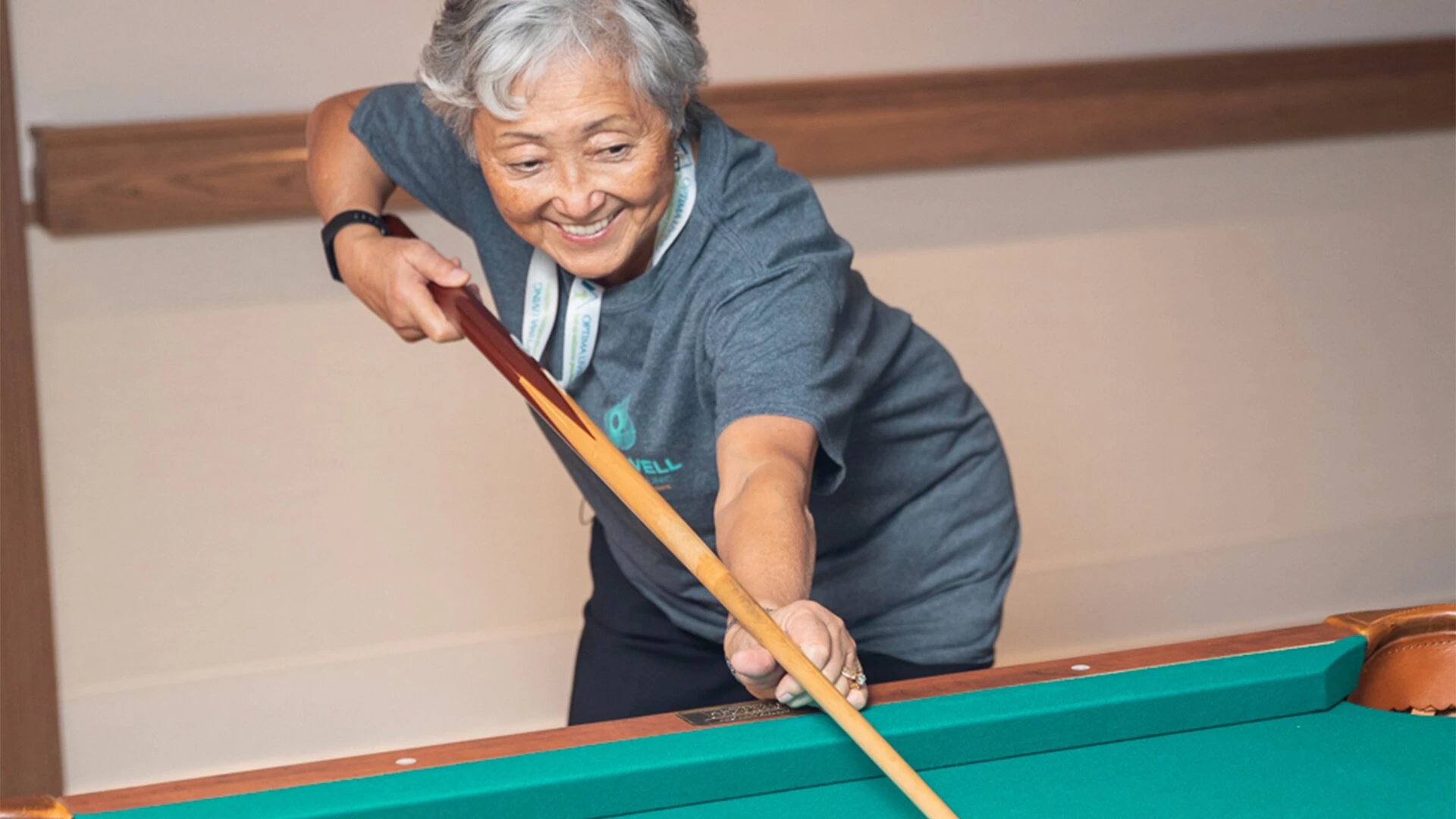 A senior woman playing pool in senior housing