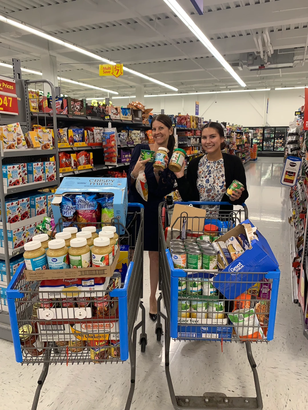 Two staff members picking up grocery carts full of food for Wisteria Place senior home.