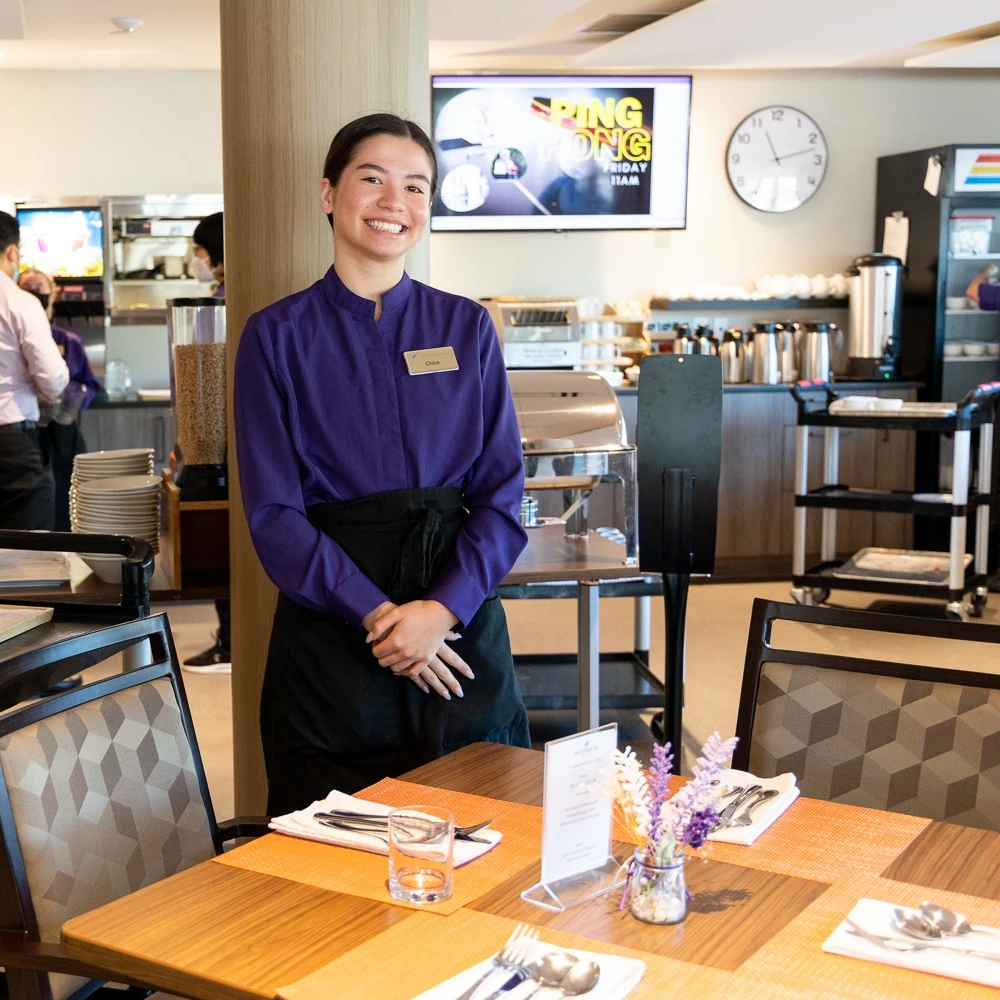 A staff member of a senior home smiling and ready to help serve residents.