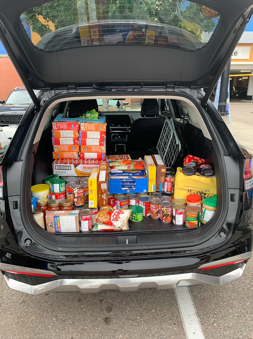 A trunk of an SUV filled with different kinds of food, both canned and boxed. For a retirement home to donate.