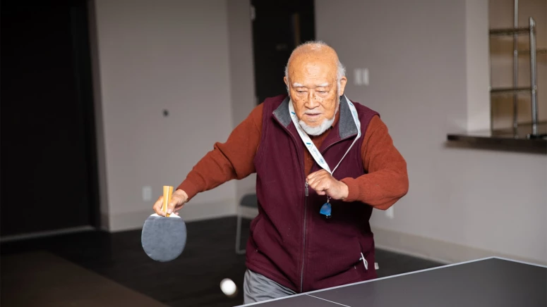 An elderly man playing ping pong